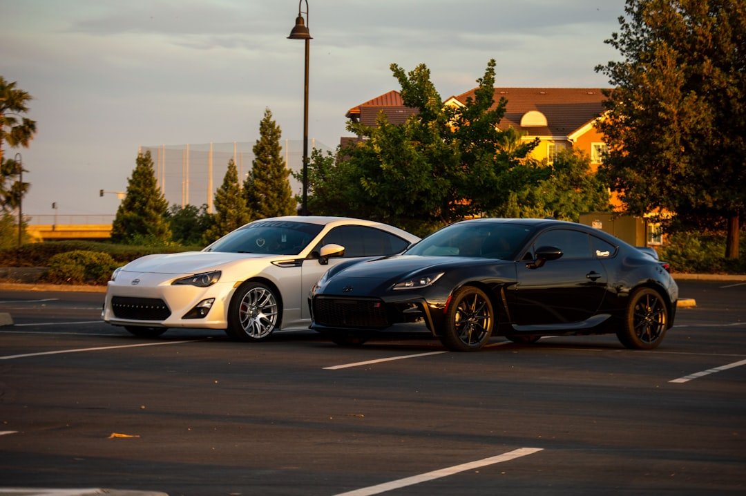 two-cars-parked-in-a-parking-lot-next-to-each-other-n85i6iflhv4